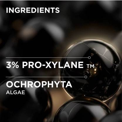 Ingredients graphic showing glossy black spheres with white text reading 'INGREDIENTS', '3% PRO-XYLANE TM', and 'OCHROPHYTA ALGAE' on a dark abstract background.
