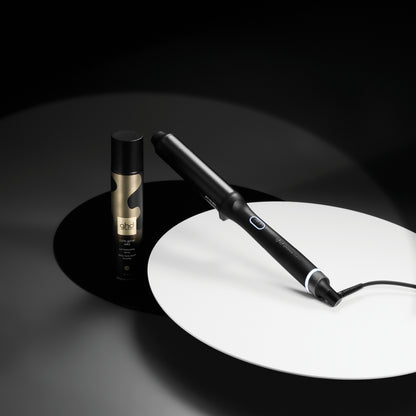 Hair straightener and bottle on a dark background